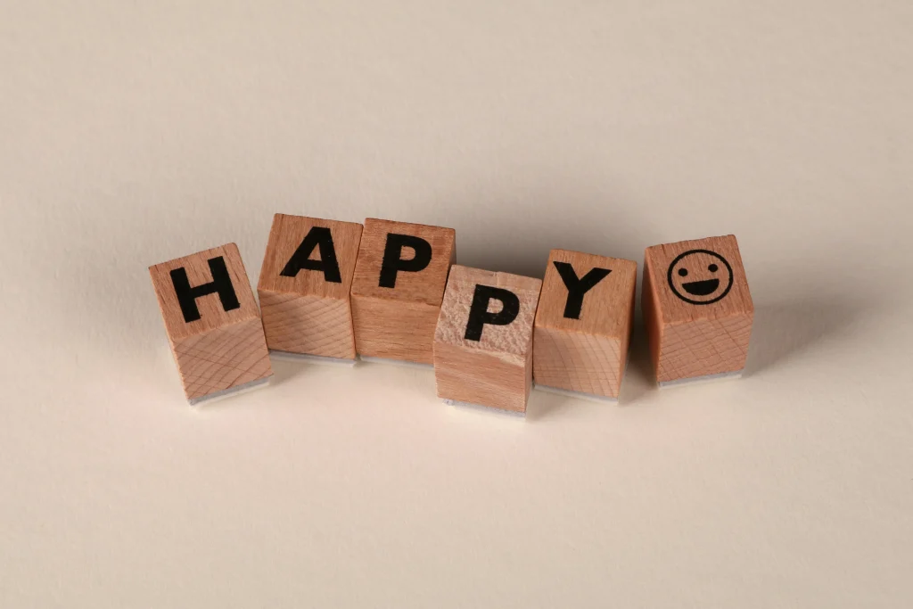 Blocs en bois avec le mot 'HAPPY', symbolisant l'état d'esprit de l'approche de l'accompagnement.