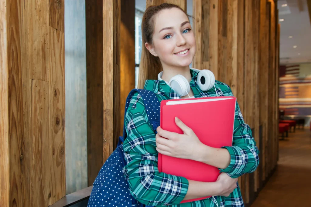 Jeune femme souriante tenant des dossiers, symbolisant l'orientation scolaire et professionnelle.